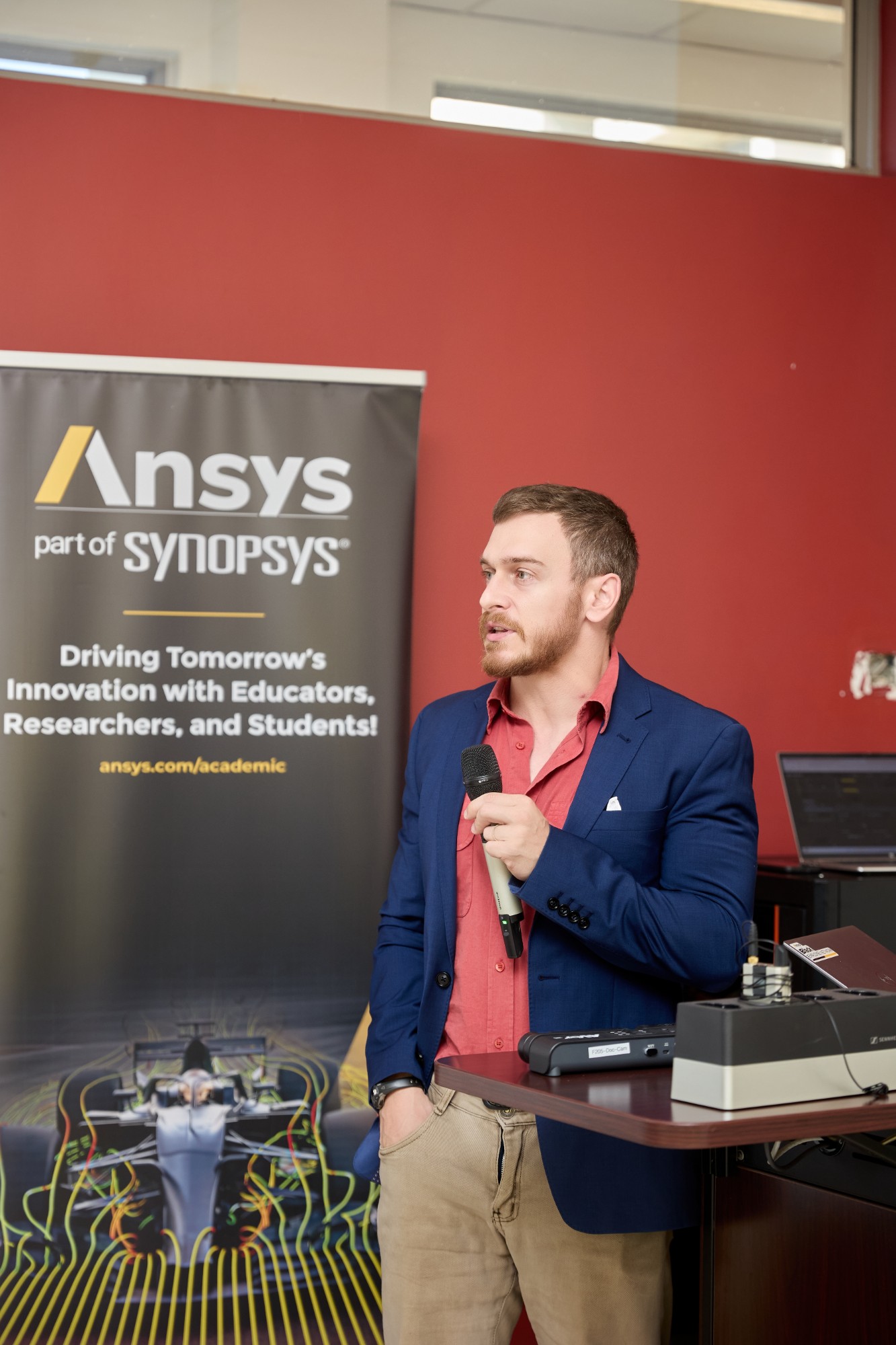 Industry speaker presenting beside an Ansys banner